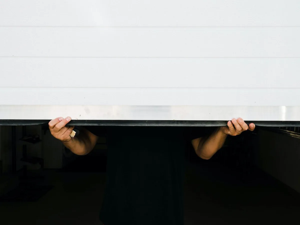 Hands holding a garage door up